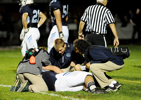 Athletic trainer and hurt football player.